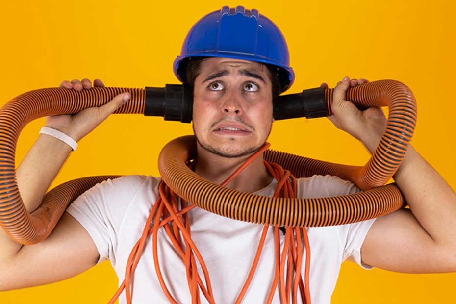 photo of stressed looking man holding industrial hose in both hands