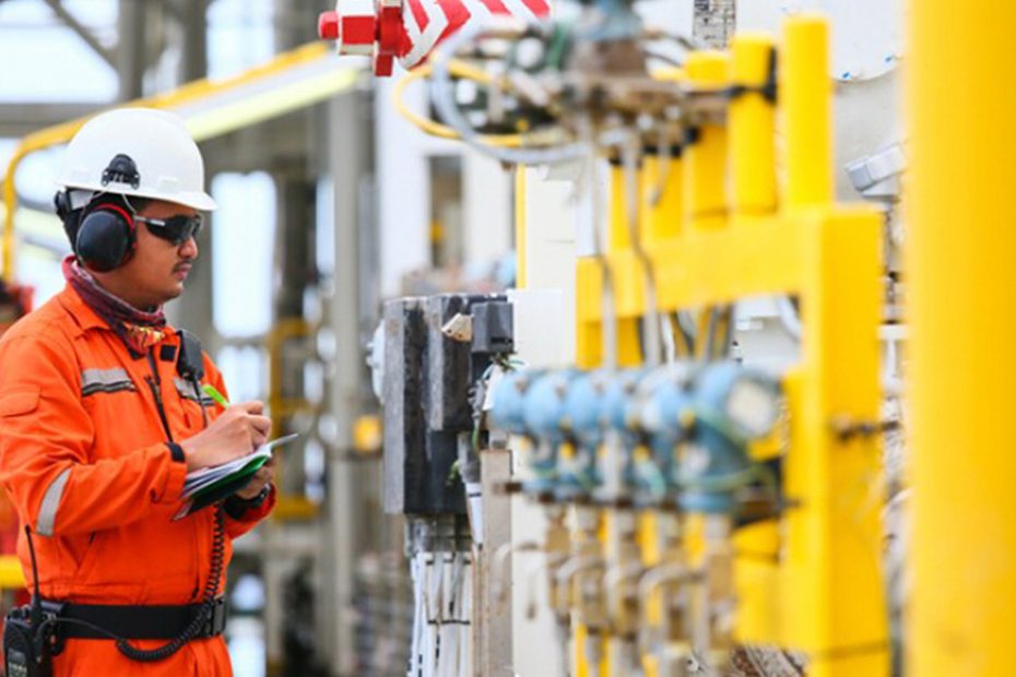 photo of employee in safety gear inspecting equipment